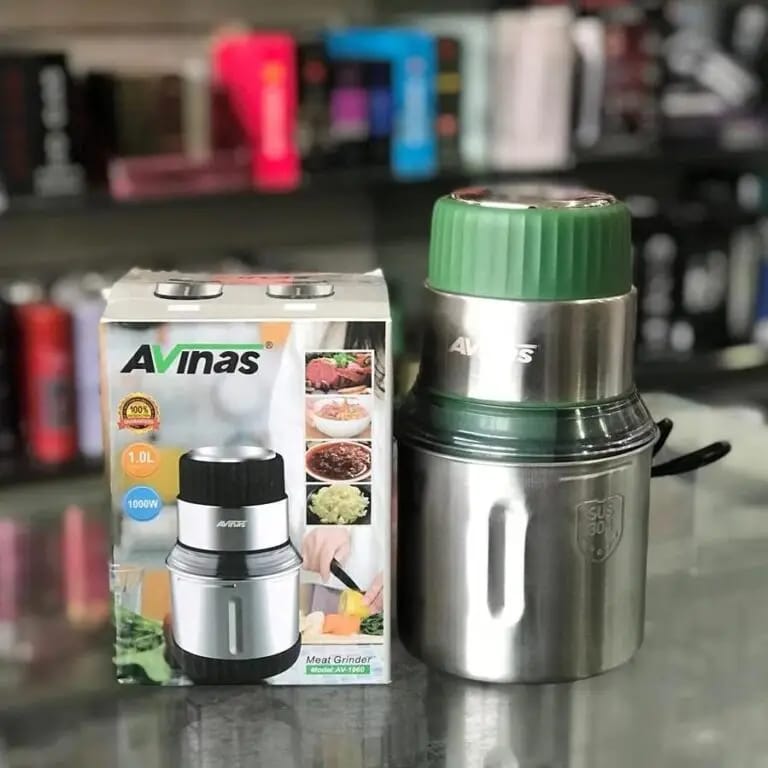 Stainless steel food processor with green lid and Avinas packaging on a blurred background